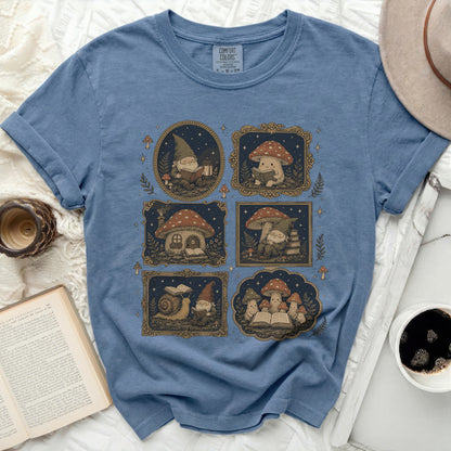 Blue t-shirt with a repeated pattern of gnomes and mushrooms reading books.