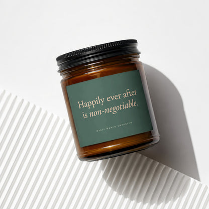 Amber glass candle with dark green label reading "Happily ever after is non-negotiable."