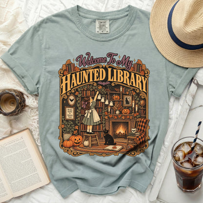 T-shirt with "Welcome To My Haunted Library" graphic featuring a girl, cat, pumpkins, and fireplace.