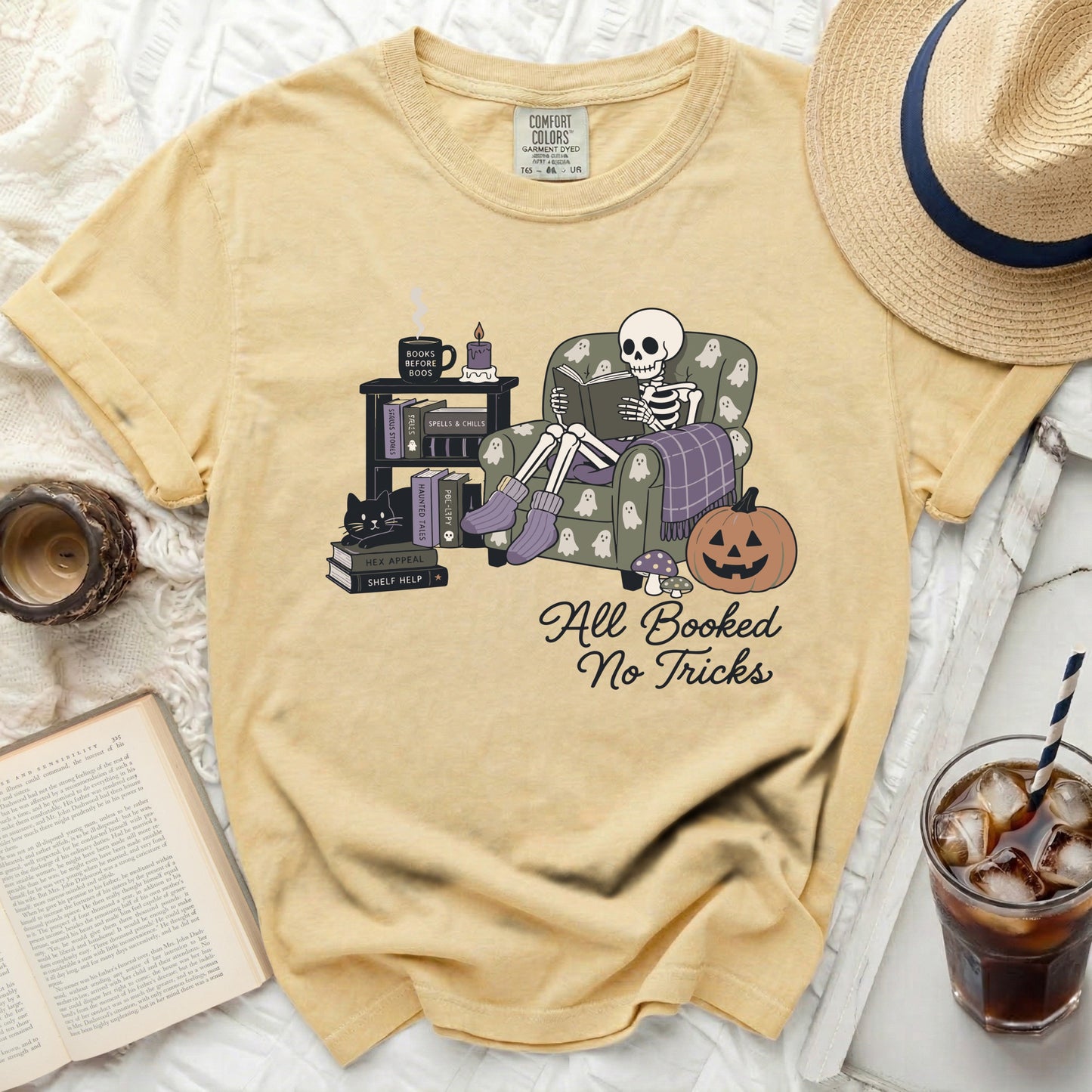 Skeleton in armchair reading book with "All Booked No Tricks" text.