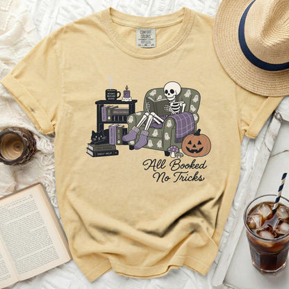 Skeleton in armchair reading book with "All Booked No Tricks" text.