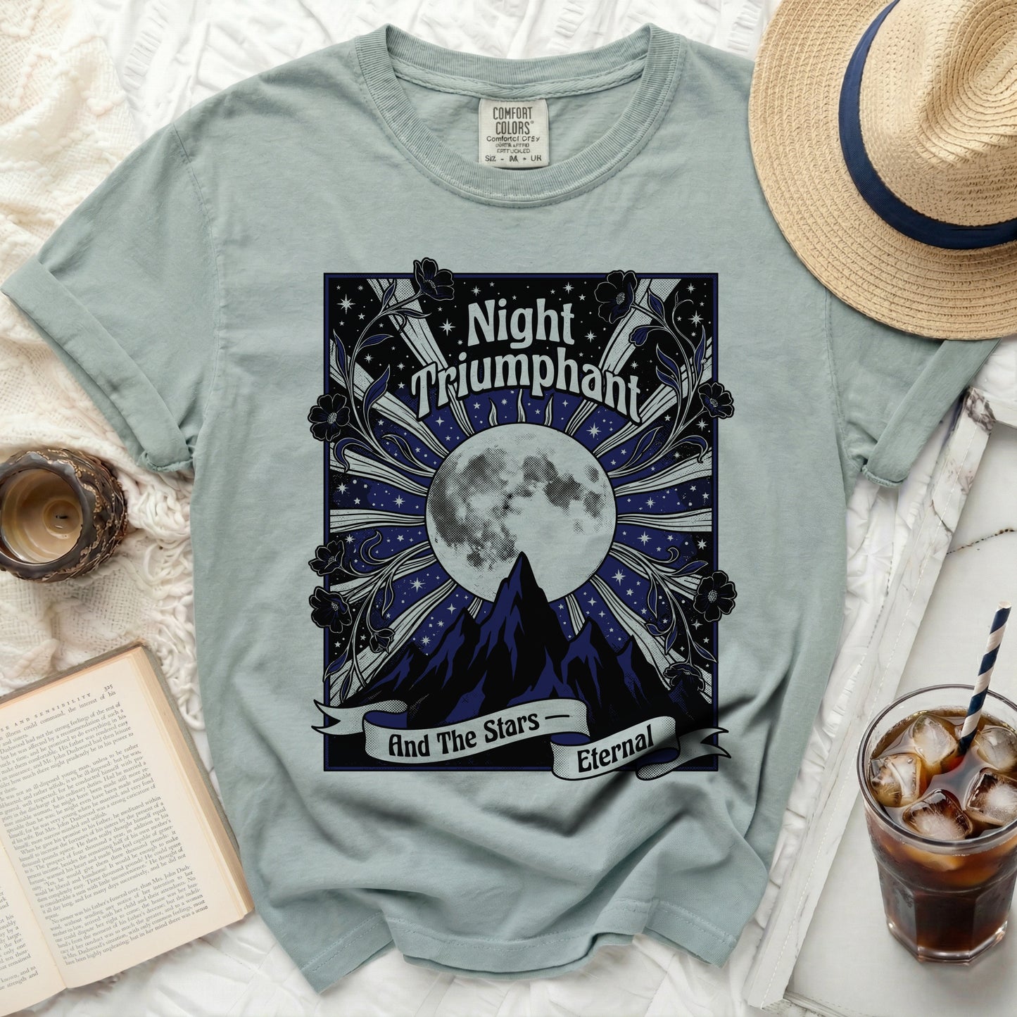 Light blue t-shirt with "Night Triumphant And The Stars Eternal" moon and mountain graphic.