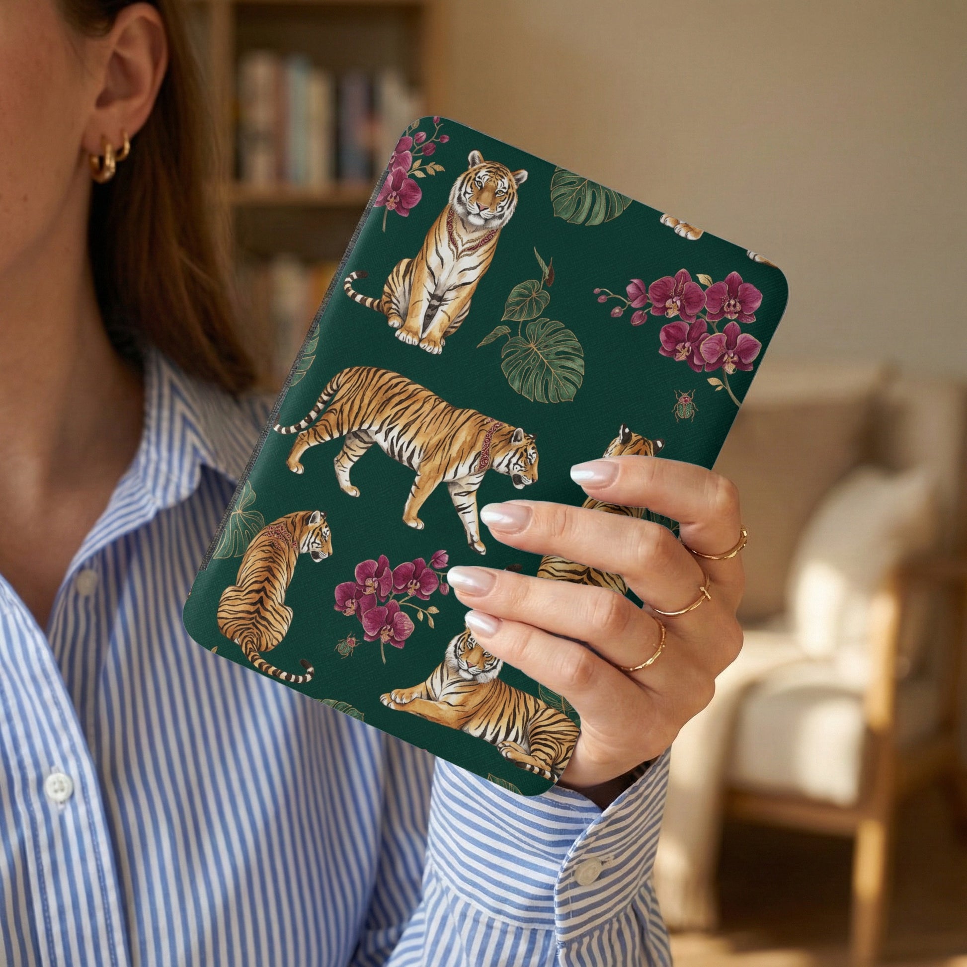 Case with tigers and orchids pattern on dark green background being held by a person.