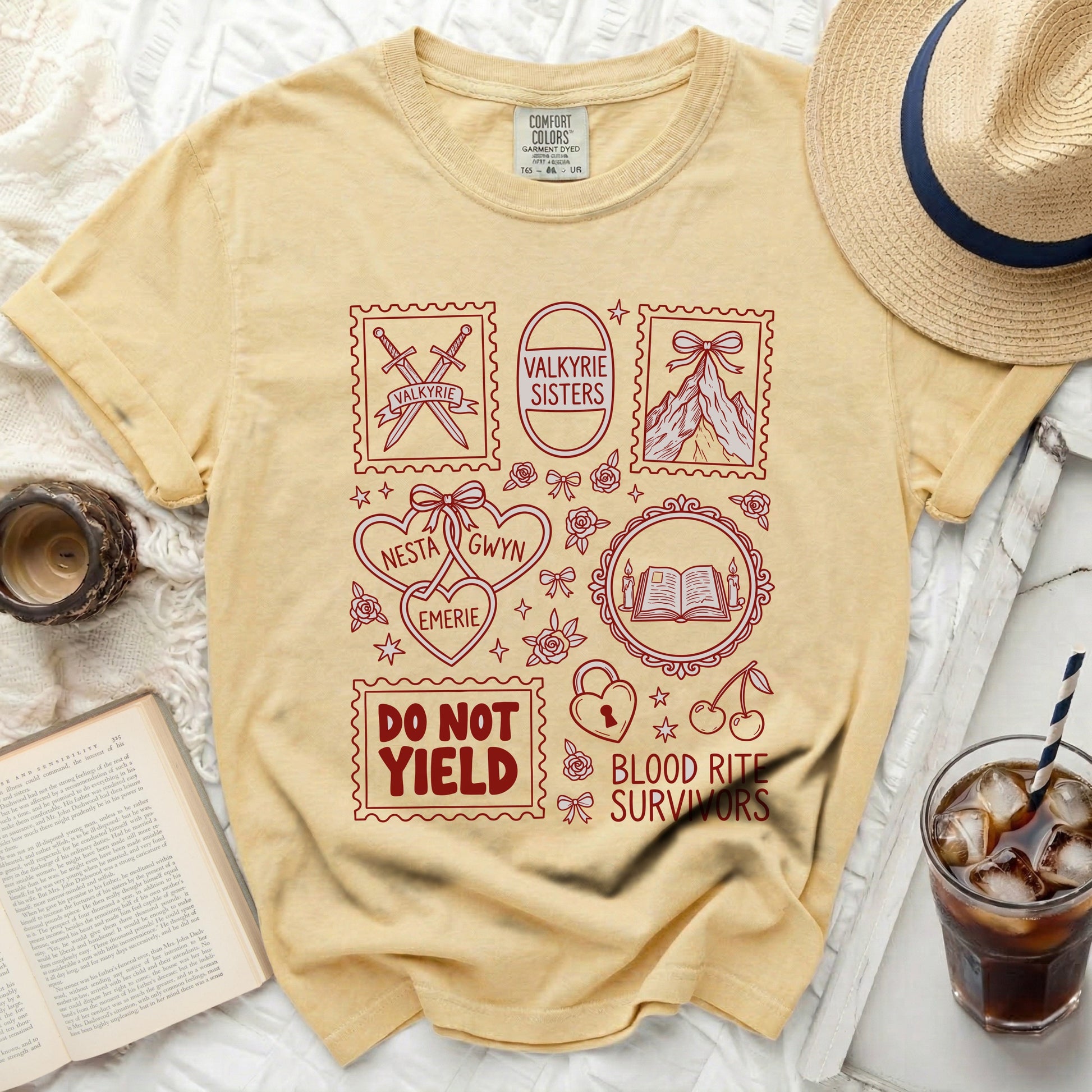 Yellow t-shirt with red graphic design including swords, mountains, hearts, books, and text.