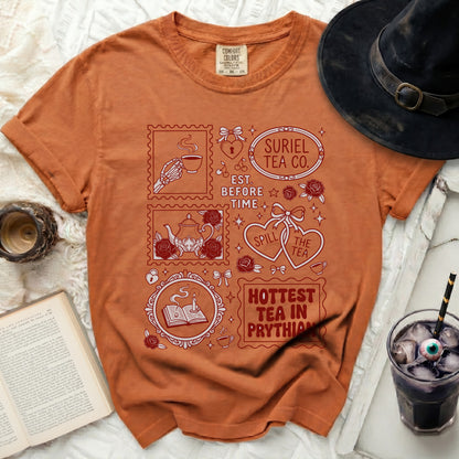Orange t-shirt with red graphic designs and text: Suriel Tea Co., Est. Before Time, Spill the Tea, Hottest Tea in Prythian.