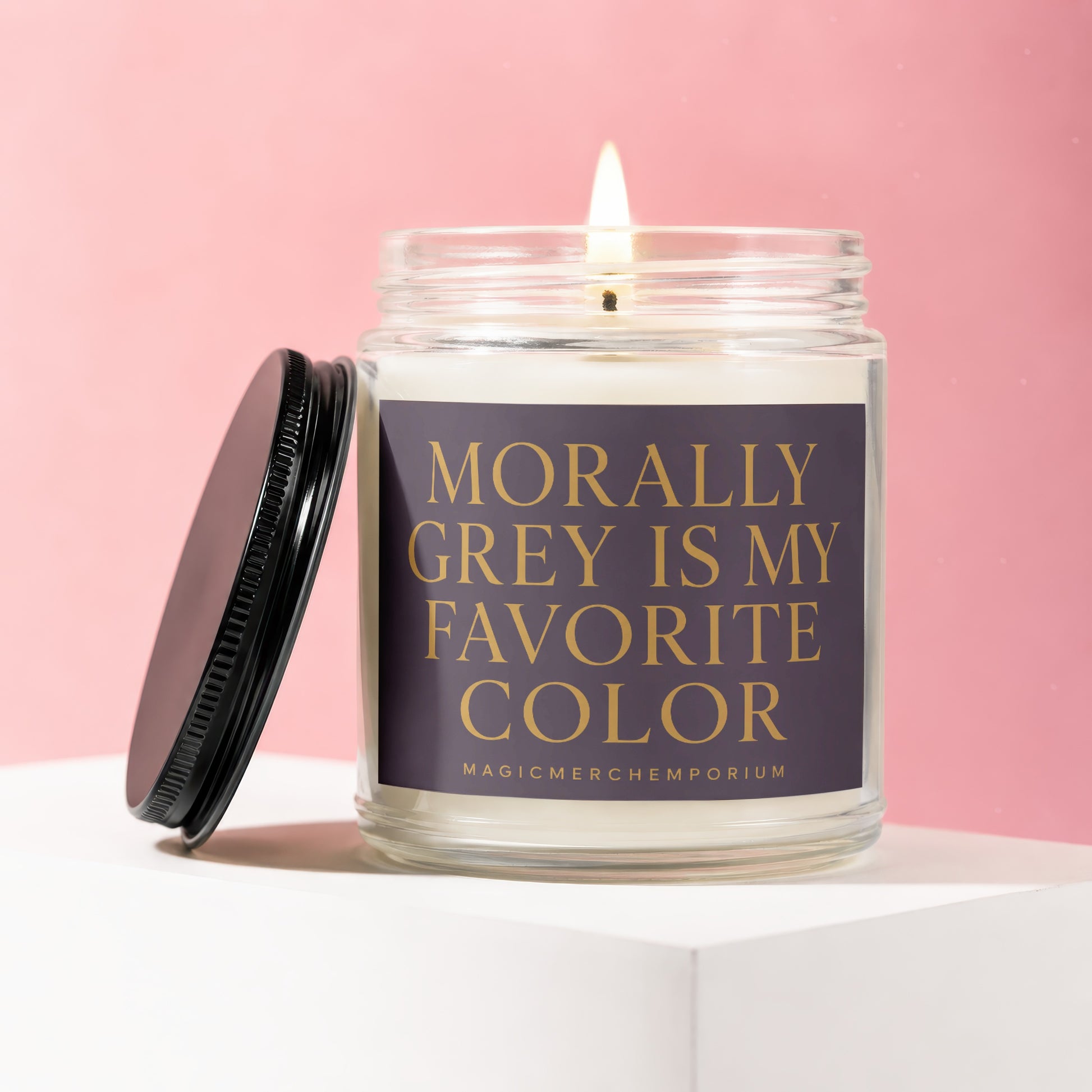 Glass jar candle with lit wick and dark lid, reading "Morally Grey Is My Favorite Color."