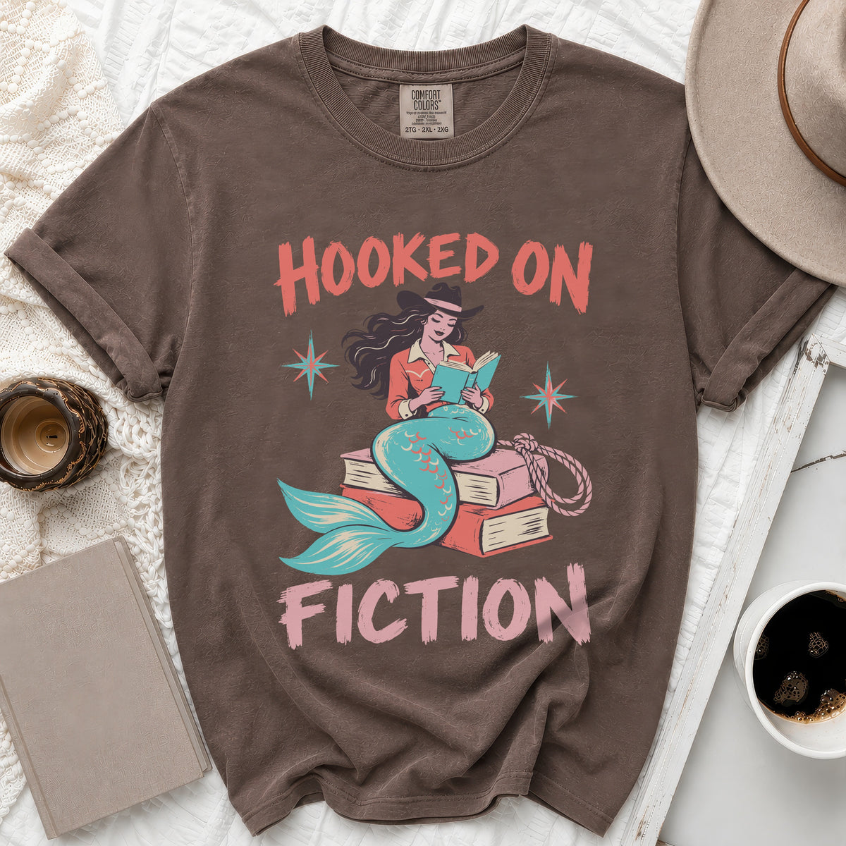 Brown t-shirt with "Hooked on Fiction" text and a mermaid reading a book.