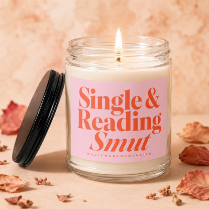 Lit glass candle with pink label that reads "Single & Reading Smut".