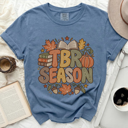 TBR SEASON graphic with books, pumpkin, leaves, and acorns on a blue t-shirt.