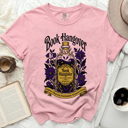 Pink t-shirt with "Book Hangover" potion graphic and bookish symptoms.