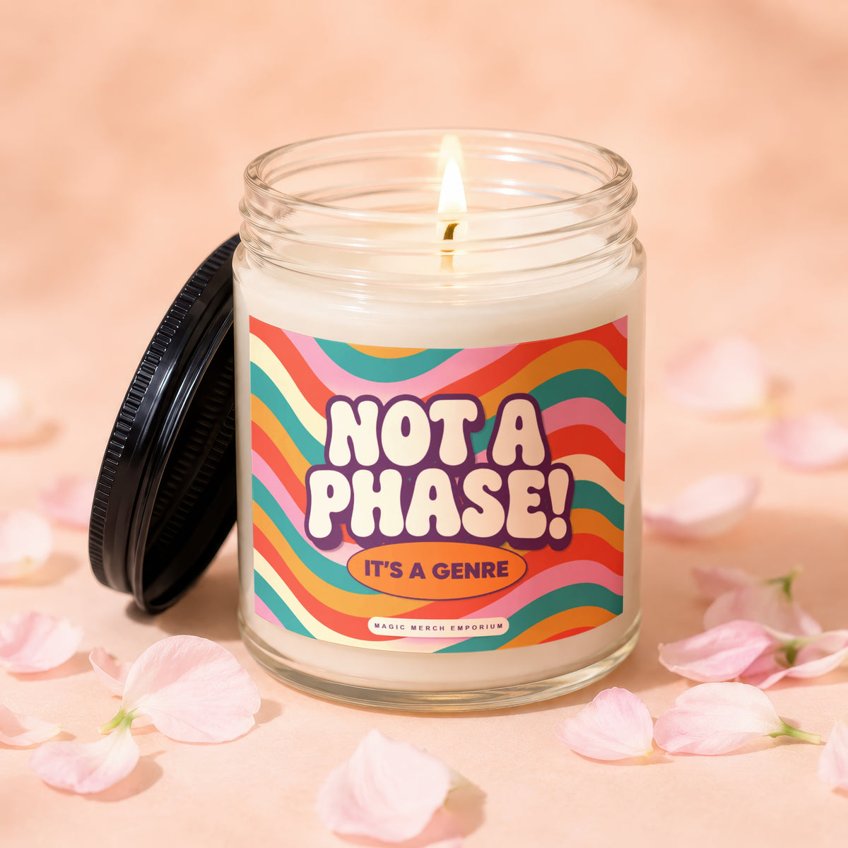 Glass candle with lit wick and "NOT A PHASE! IT'S A GENRE" label.
