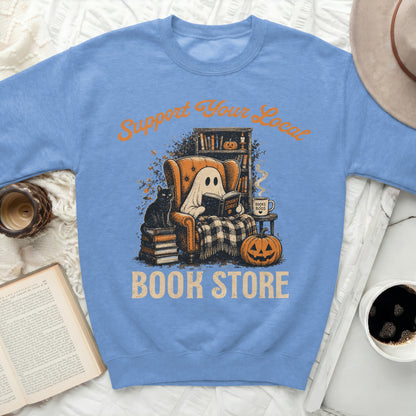Ghost reading "Spooky Stories" next to a pumpkin and books, with text "Support Your Local Book Store".