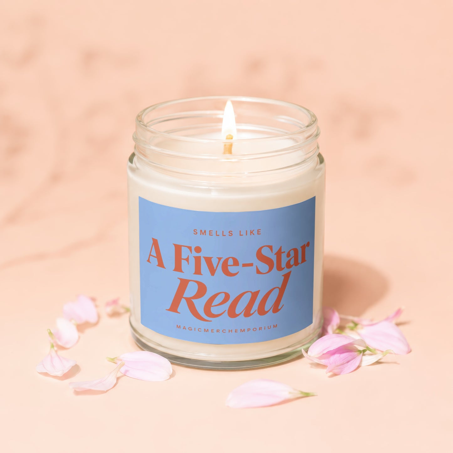 Lit candle in glass jar with blue label reading "Smells Like A Five-Star Read".