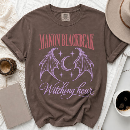 Brown t-shirt with "MANON BLACKBEAK Witching hour" text and winged moon graphic.