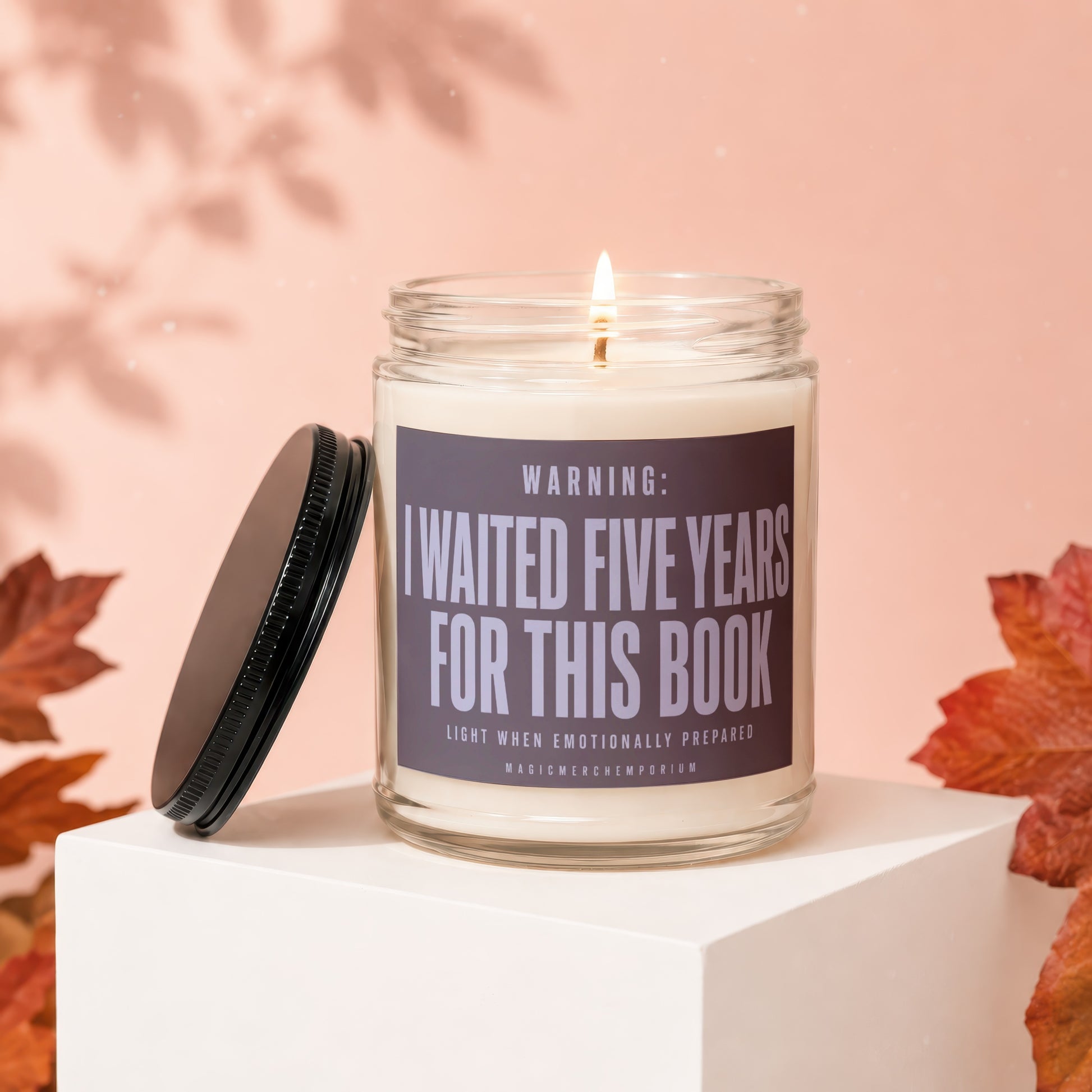 Candle with lid off, "I waited five years for this book" text, lit wick.