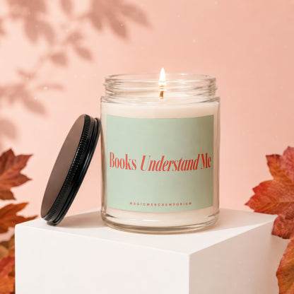 Glass candle with lit wick, light green label reading "Books Understand Me".
