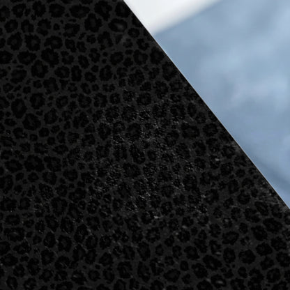 Black and grey leopard print fabric diagonally divided from a light blue background.
