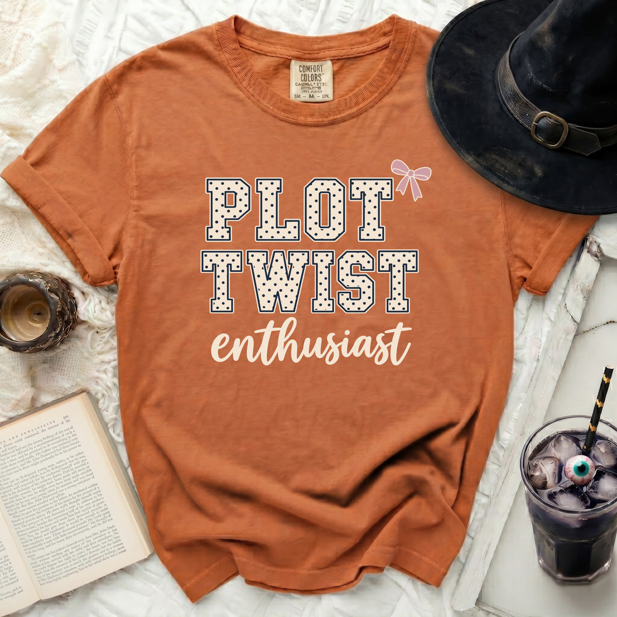 Orange t-shirt with "Plot Twist Enthusiast" text and a pink bow.