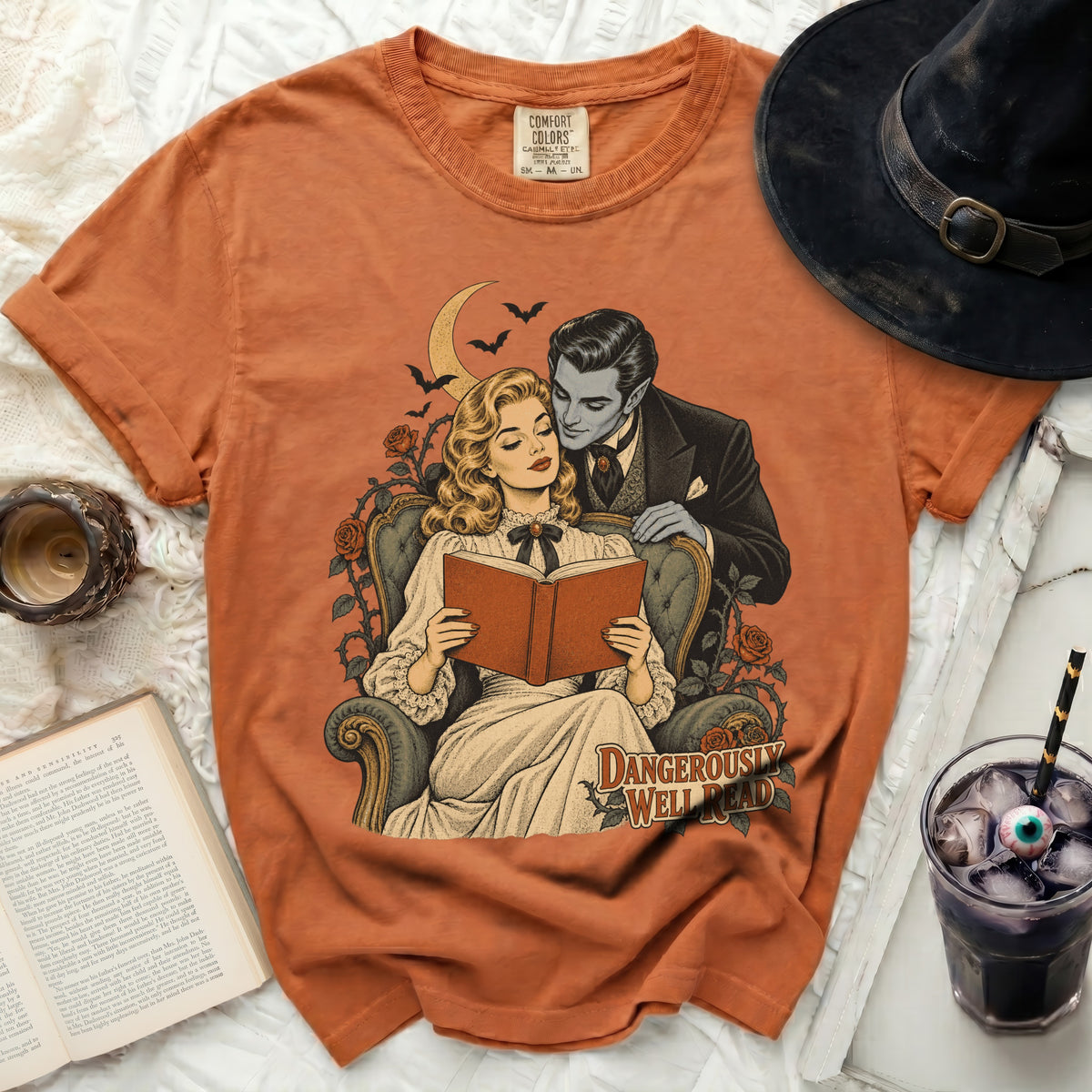 Orange t-shirt with a vintage style illustration of a vampire embracing a woman reading.