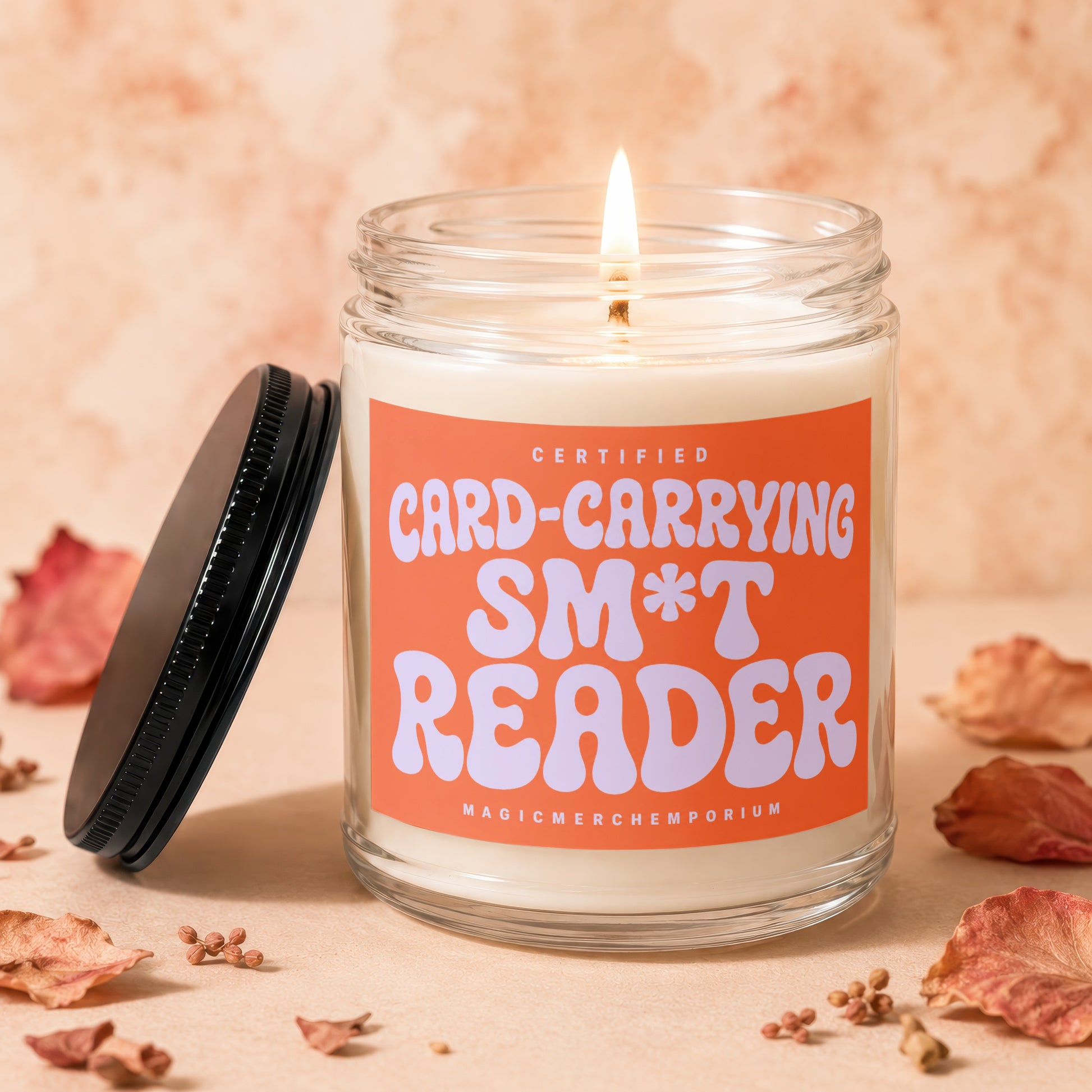 Lit candle in glass jar with "Certified Card-Carrying S*&* Reader" label.