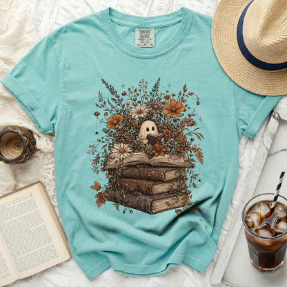 Ghost reading a book surrounded by flowers on a turquoise t-shirt.