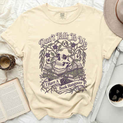 Cream t-shirt with a skull, books, flowers, and the text "Don't Talk To Me I Have A Book Hangover".