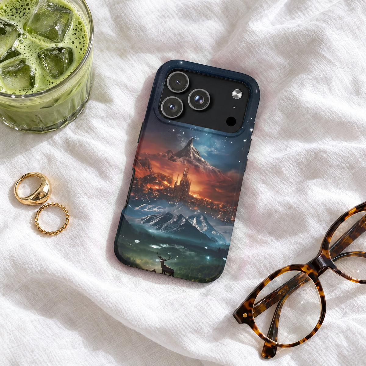 A smartphone case featuring a fantasy landscape of mountains and a castle, resting on white fabric.