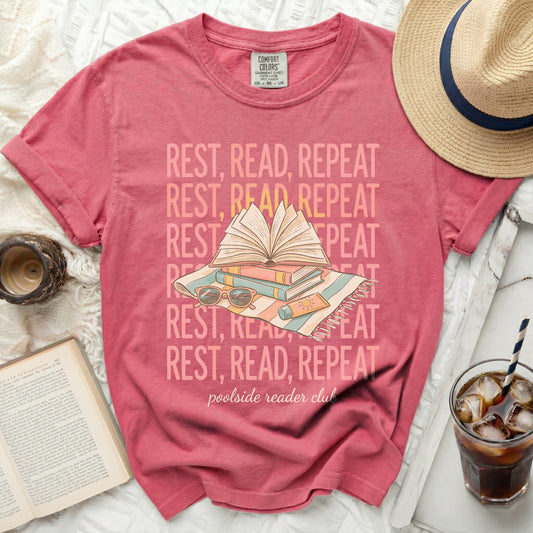 T-shirt with "Rest, Read, Repeat" text and a beach towel with books and sunglasses.