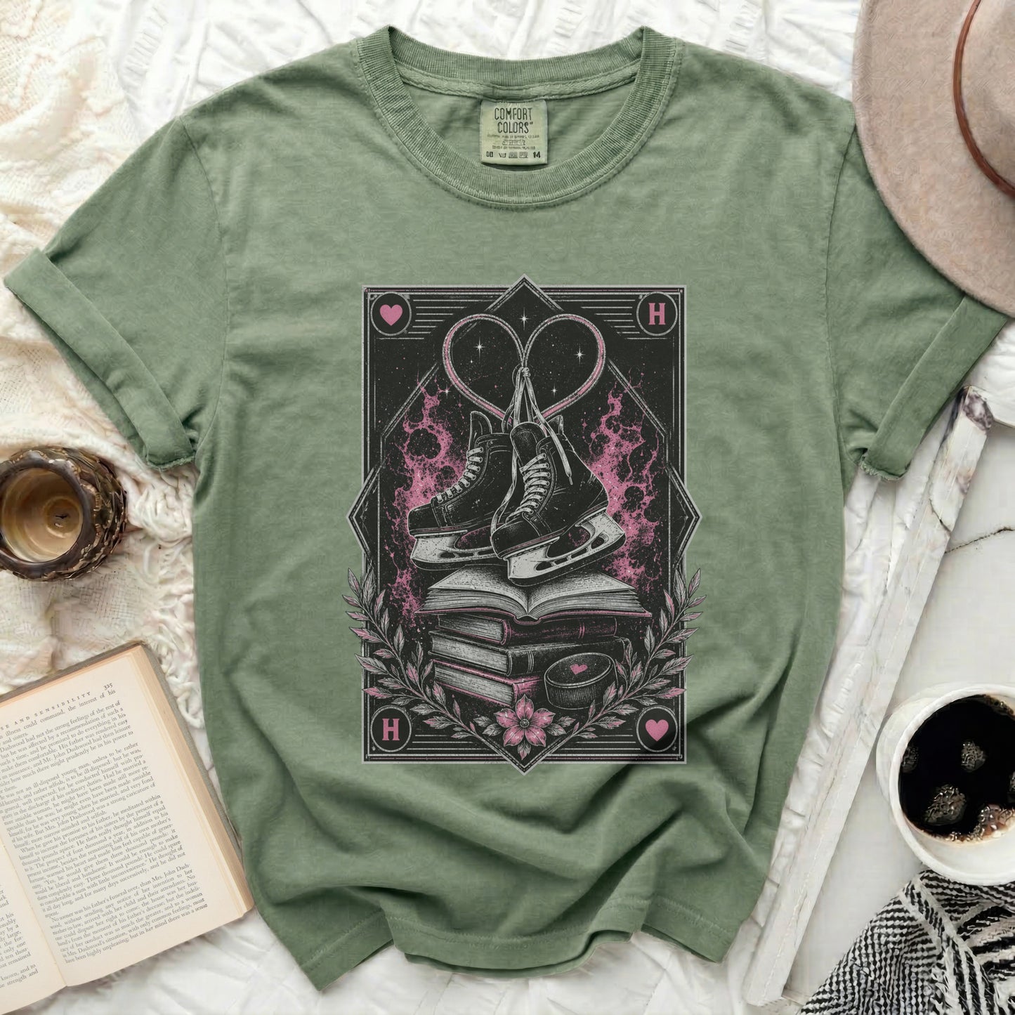 Green t-shirt with ice skates and hearts graphic, book, and coffee cup.