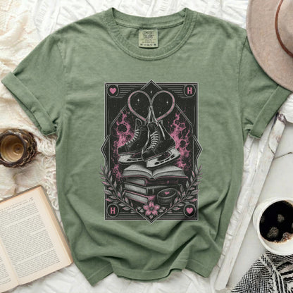 Green t-shirt with ice skates and hearts graphic, book, and coffee cup.