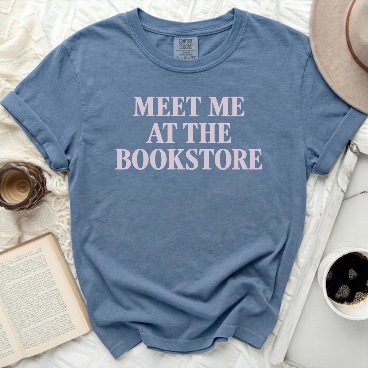 Blue t-shirt with "MEET ME AT THE BOOKSTORE" printed in light pink.