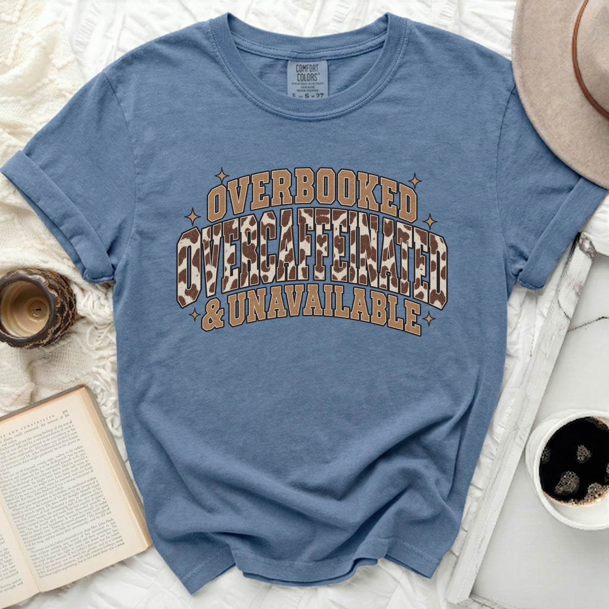 Blue t-shirt with text "OVERBOOKED, OVERCAFFEINATED & UNAVAILABLE".