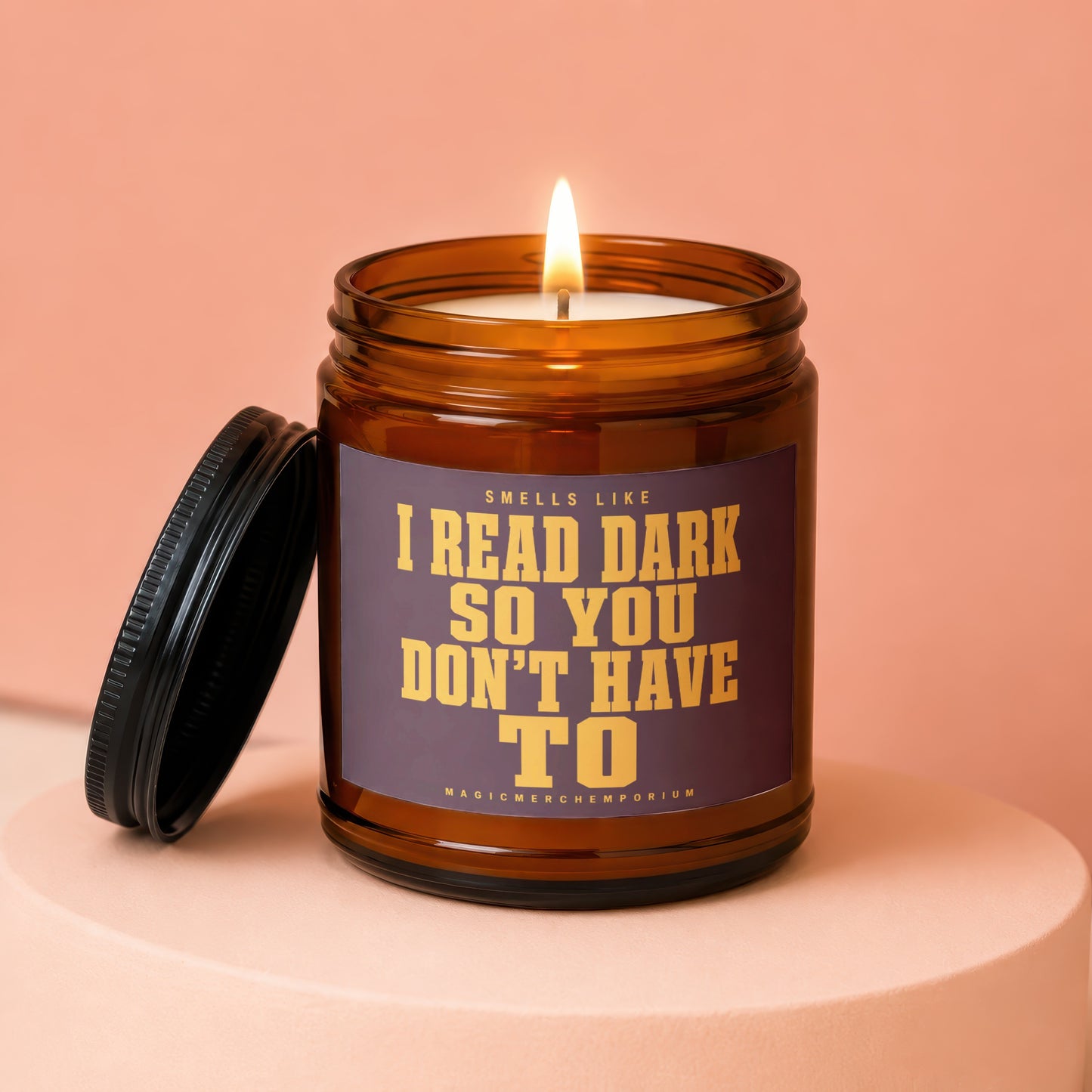 Brown glass candle with lit flame and dark lid, reads "Smells Like I Read Dark So You Don't Have To".