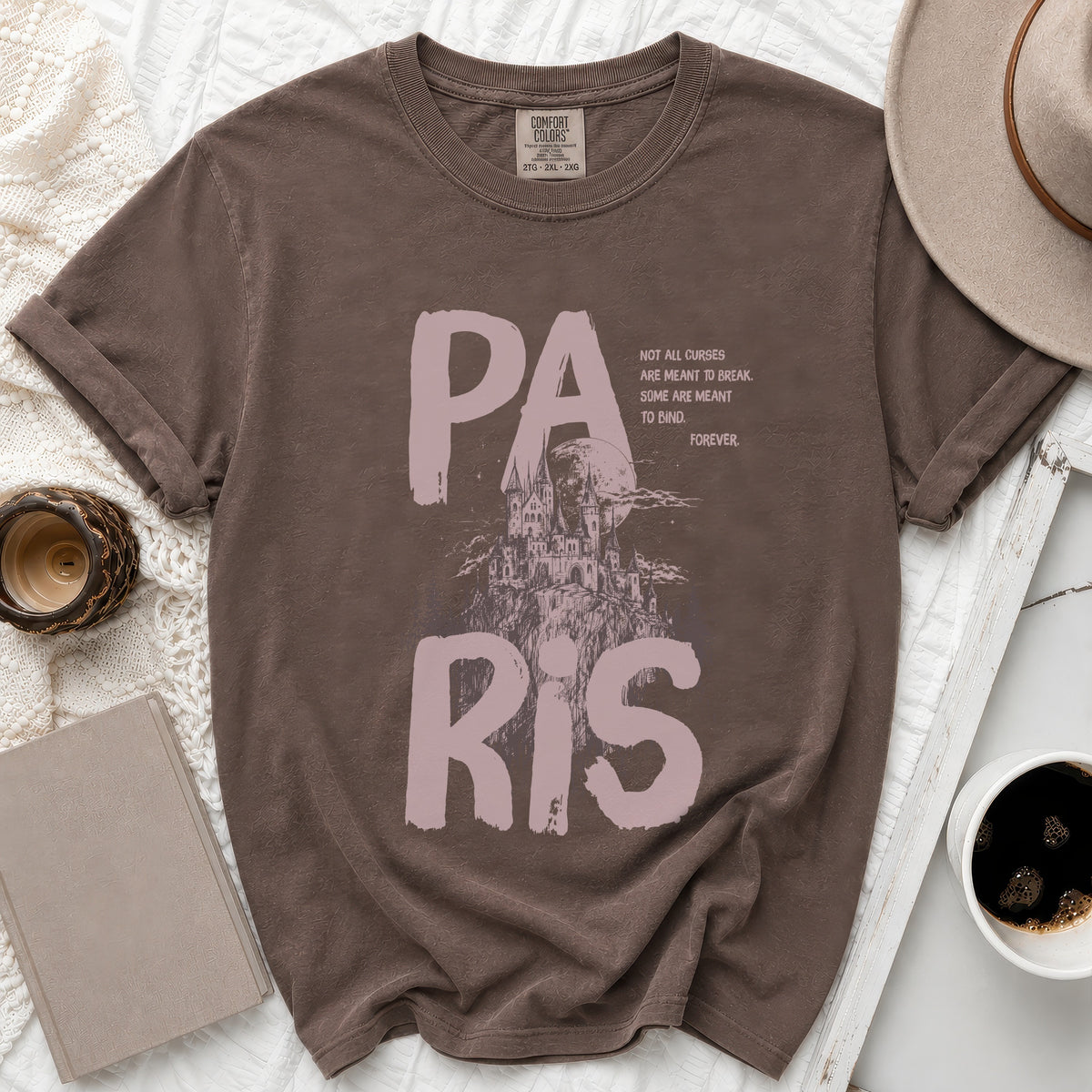 Brown t-shirt with "PARIS" text and castle graphic, and the quote "NOT ALL CURSES ARE MEANT TO BREAK. SOME ARE MEANT TO BIND. FOREVER."