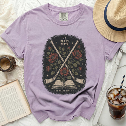 T-shirt with crossed hockey sticks, roses, and text "HE PLAYS DIRTY. SHE READS DIRTIER."