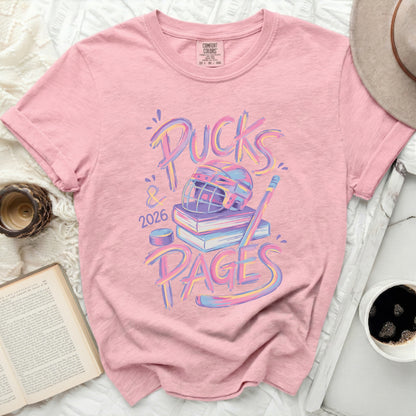Pink t-shirt with "Pucks & Pages 2026" and hockey gear graphic.
