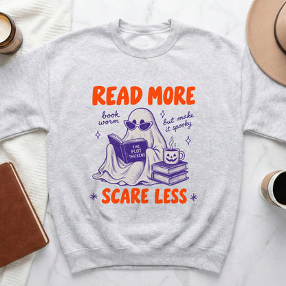 Light grey sweatshirt with ghost reading a book and text "Read More Scare Less".