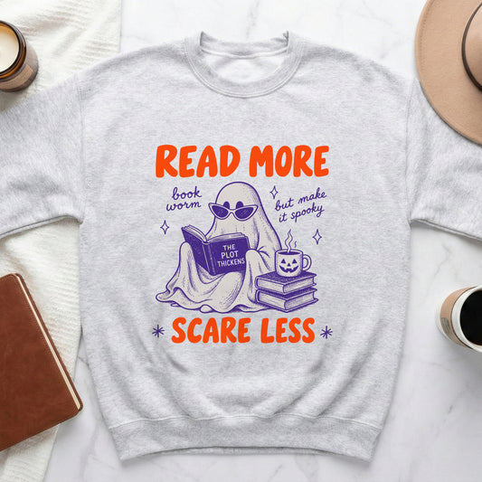 Light grey sweatshirt with ghost reading a book and text "Read More Scare Less".