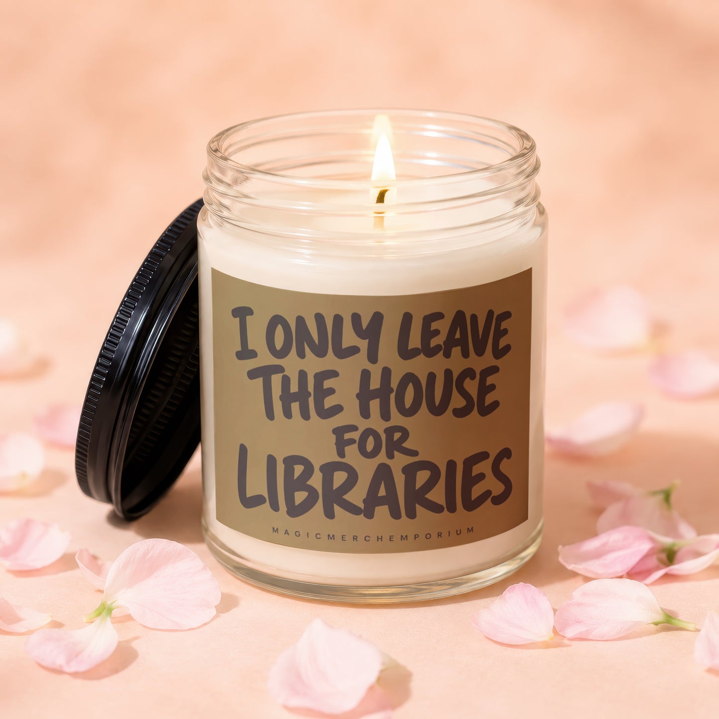 Candle with lit wick and black lid, reads "I ONLY LEAVE THE HOUSE FOR LIBRARIES".