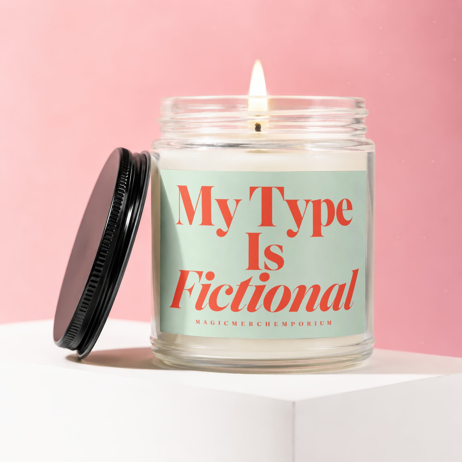 Glass candle with lit wick, teal label reading "My Type Is Fictional".