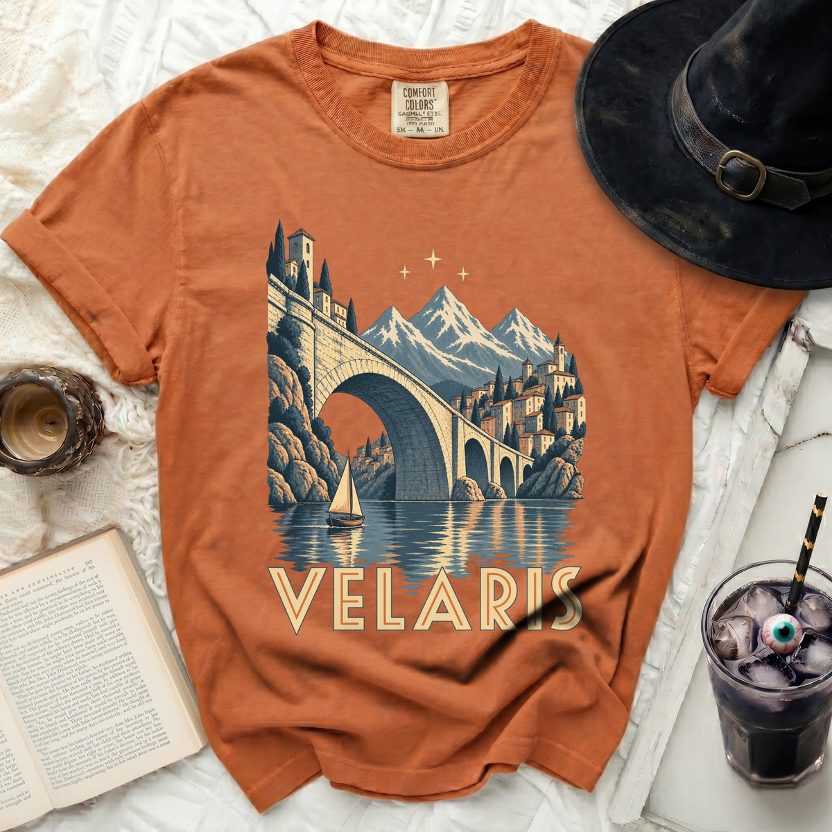 Orange t-shirt with Velaris artwork featuring a bridge, mountains, and a sailboat.