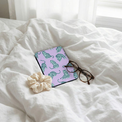 Purple case with teal tiger pattern, glasses, and scrunchie on white linens.