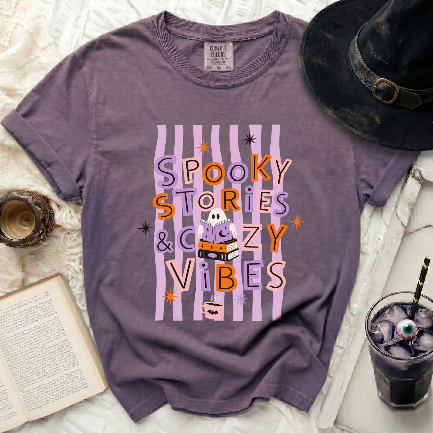 Purple t-shirt with "Spooky Stories & Cozy Vibes" Halloween graphic.