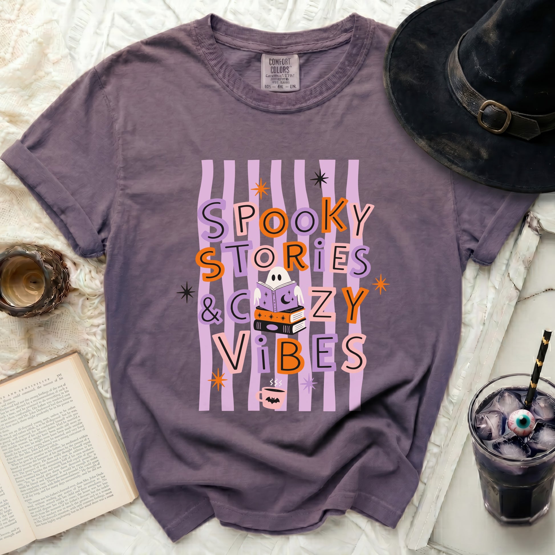 Purple t-shirt with "Spooky Stories & Cozy Vibes" Halloween graphic.
