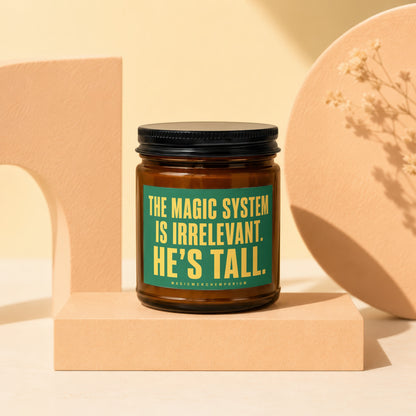Brown glass jar candle with a green label reading "THE MAGIC SYSTEM IS IRRELEVANT. HE'S TALL."