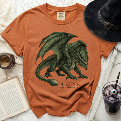 Orange t-shirt with a green dragon graphic and the text "TEINE MIRA SORRENGALL".