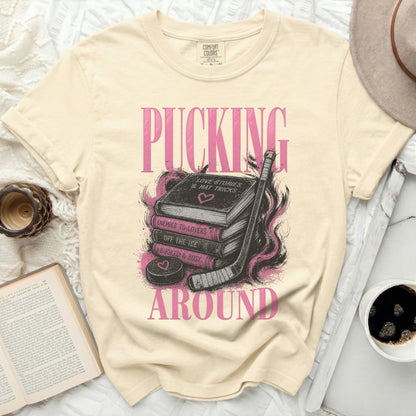 Cream t-shirt with pink text "PUCKING LOVE STORIES & HAT TRICKS" and hockey puck.