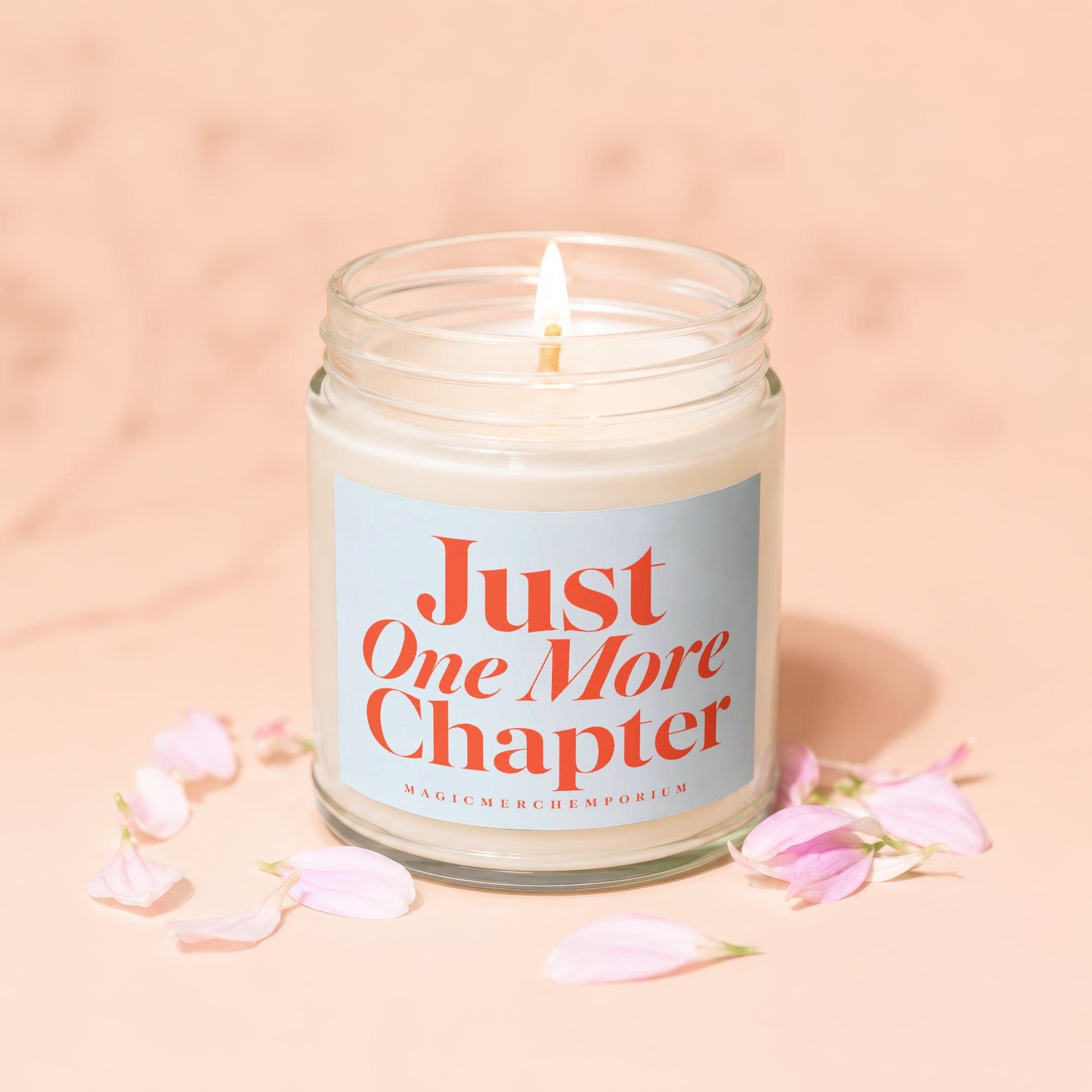 Lit candle in glass jar with "Just One More Chapter" text and pink petals.