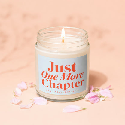 Lit candle in glass jar with "Just One More Chapter" text and pink petals.