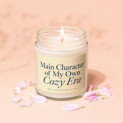 Lit candle in a glass jar with a yellow label reading "Main Character of My Own Cozy Era".